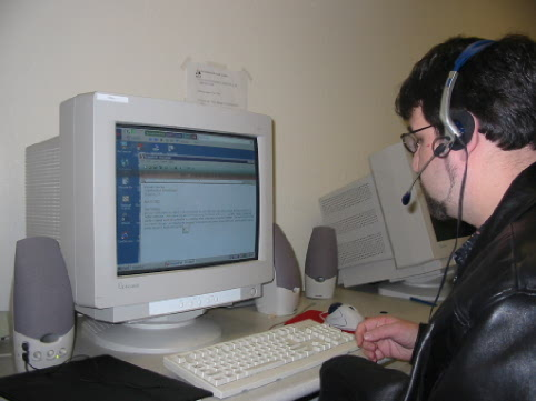 Photo of student using voice recognition. Student is sitting at a computer with headset on his head.